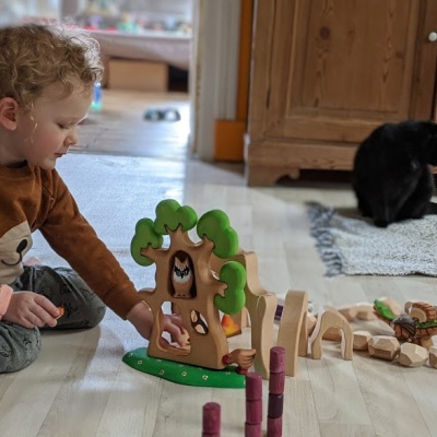 A child holding the treehouse and incorporating it into their imaginative forest play scene.
