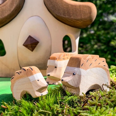 The toy photographed outdoors, nestled amongst real leaves or under a small bush.