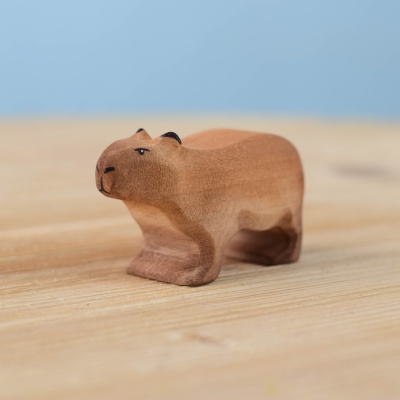 Handmade wooden capybara toy on a wooden surface.