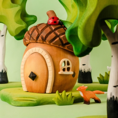 Child hand placing the small wooden chimney onto the roof of the acorn house toy