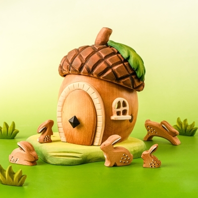 Child playing with wooden bunnies around a handmade acorn house toy