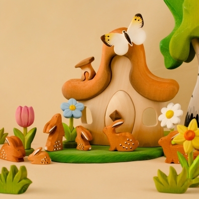 Whimsical wooden fairy house surrounded by bunny figures, a pink tulip, and a bright yellow wooden daffodil toy