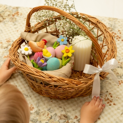 Woven basket filled with pastel wooden eggs and a blue toy forget-me-not