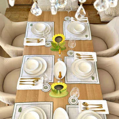 An overhead view of a dining table beautifully set with plates and cutlery, featuring wooden sunflower decorations as centerpieces.