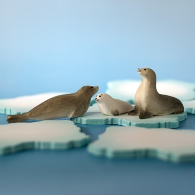 BumbuToys wooden seal figures arranged on blue ice platforms for Waldorf small world play.