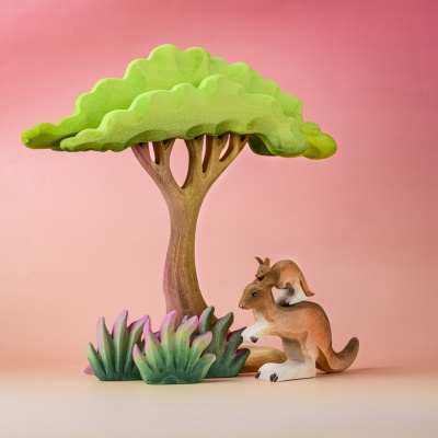 Wooden kangaroo and joey toy under a green tree with forest scenery