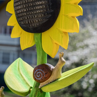 Handcrafted wooden snail climbing on a large wooden sunflower toy by Bumbu Toys