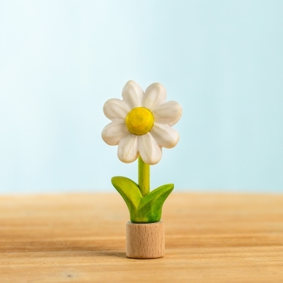 Hand painted wooden daisy toy standing against a light blue background