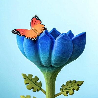 Wooden butterfly perched on a blue flower