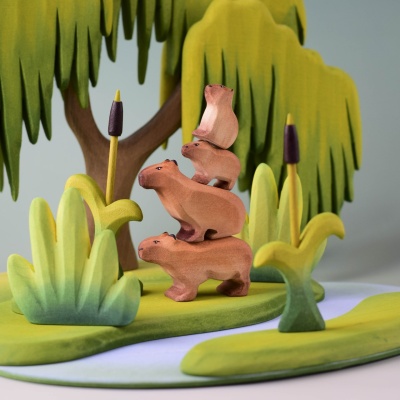 Stackable wooden capybaras in a nature-inspired play scene.