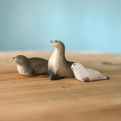 Wooden seal family set featuring a curious seal, an adult seal, and a white pup on a wood table.