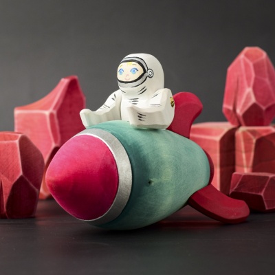 Astronaut figure sitting on the Wooden Rocket, engaging in imaginative space play.