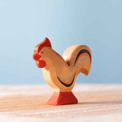 Image of a hand-carved and hand-painted wooden rooster figurine standing proudly with its wings slightly raised.
