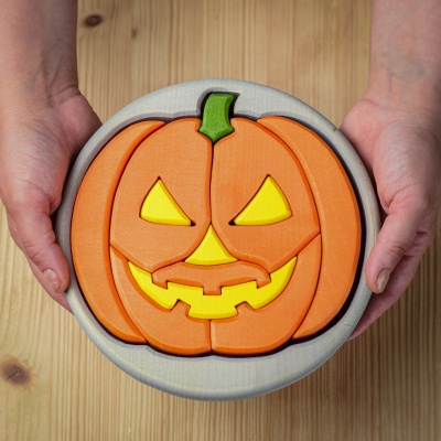 Round Halloween puzzle in a festive scene with other autumn decorations, featuring a grey base.