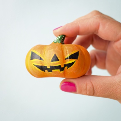 Large wooden Halloween pumpkin held in hand.