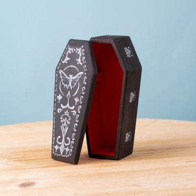 Coffin standing open, showcasing detailed white gothic designs on the lid