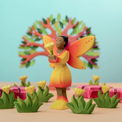 Handcrafted wooden Sunflower Fairy holding a flower, surrounded by trees and plants by Bumbu Toys