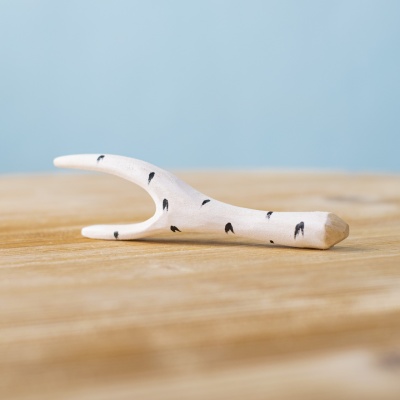 Wooden birch branch toy with black markings, placed on a wooden surface.
