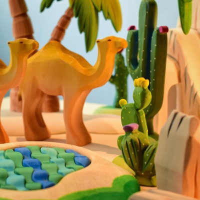 Wooden pin cushion cactus with camels and desert landscape