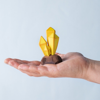 Hand holding a yellow crystal cluster toy to show size and craftsmanship.
