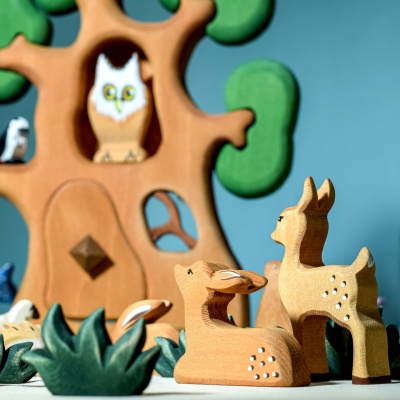 Handcrafted wooden animal figure of a resting fawn.