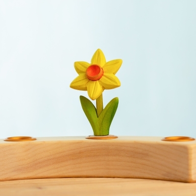 Hand-painted wooden toy daffodil with green leaves resting in a wooden celebration ring