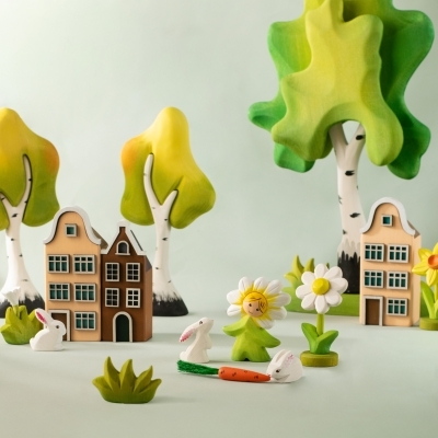 Wooden village scene with houses, birch trees, bunnies, a daisy fairy, and a yellow handcrafted daffodil toy