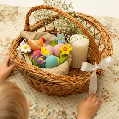 Woven basket filled with pastel Easter eggs and wooden spring toys including a pink tulip and yellow daffodil
