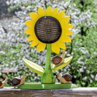 Wooden sunflower with multiple wooden snail toys on a sunny day by Bumbu Toys