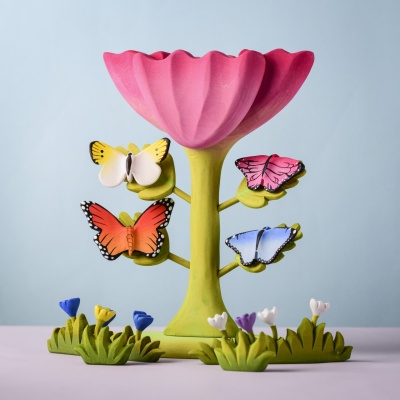 Pink butterfly perched on a flower-shaped stand with other wooden butterflies.