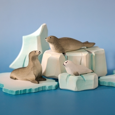 Arctic small world play scene with wooden seal family and large ice mountain backdrop.