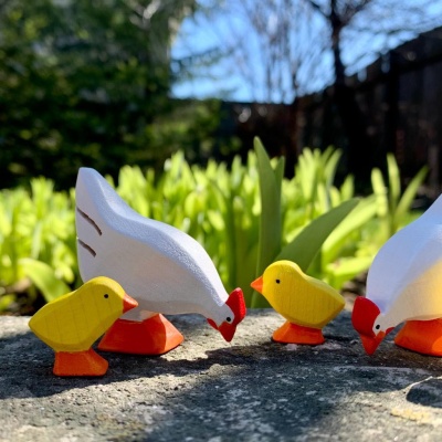Wooden Chicks playfully placed near miniature food and water dishes.