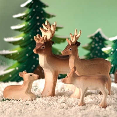 Wooden Reindeer family set featuring the Sitting Calf, Standing Calf, Doe, and Stag in a winter forest scene.