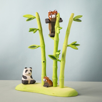 Red panda cub near bamboo tree with panda and red panda friends