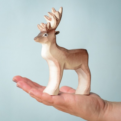 Hand holding a wooden reindeer toy.