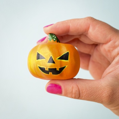 Medium wooden Halloween pumpkin held in hand.