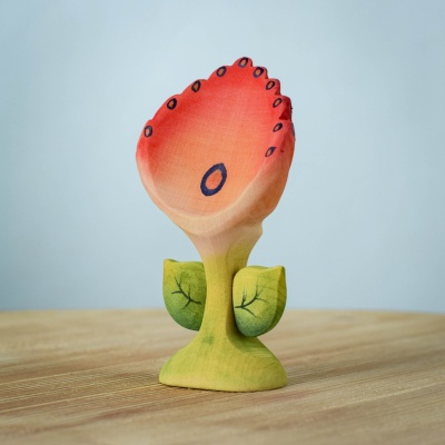 Handcrafted Spring Flower - Perla wooden toy with red and orange petals, yellow-green stem, and green leaves on a wooden table, perfect for nature-inspired play.