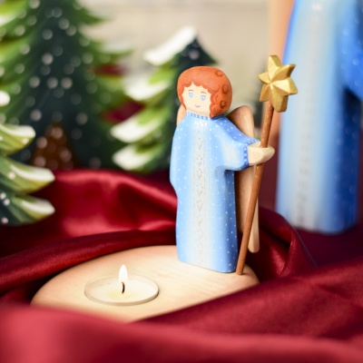 Angel Candle Holder figurine set among festive decor and pine trees.