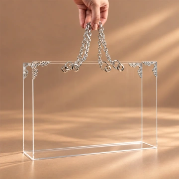 Geantă transparentă din plexiglas, ținută de mânerele din lanț metalic argintiu