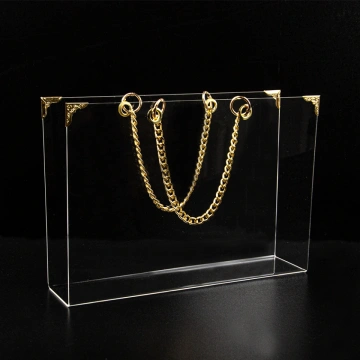 Geantă din plexiglas pentru aranjamente florale, cu accesorii decorative aurii, pe fundal negru