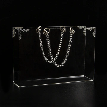 Geantă din plexiglas pentru aranjamente florale, cu accesorii decorative argintii, pe fundal negru