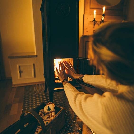 persoana incalzindu-se la soba in casa