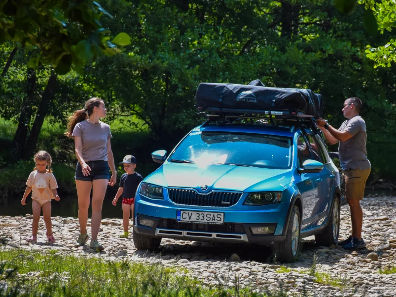 Familie lângă o mașină cu cort de acoperiș montat pe plafon