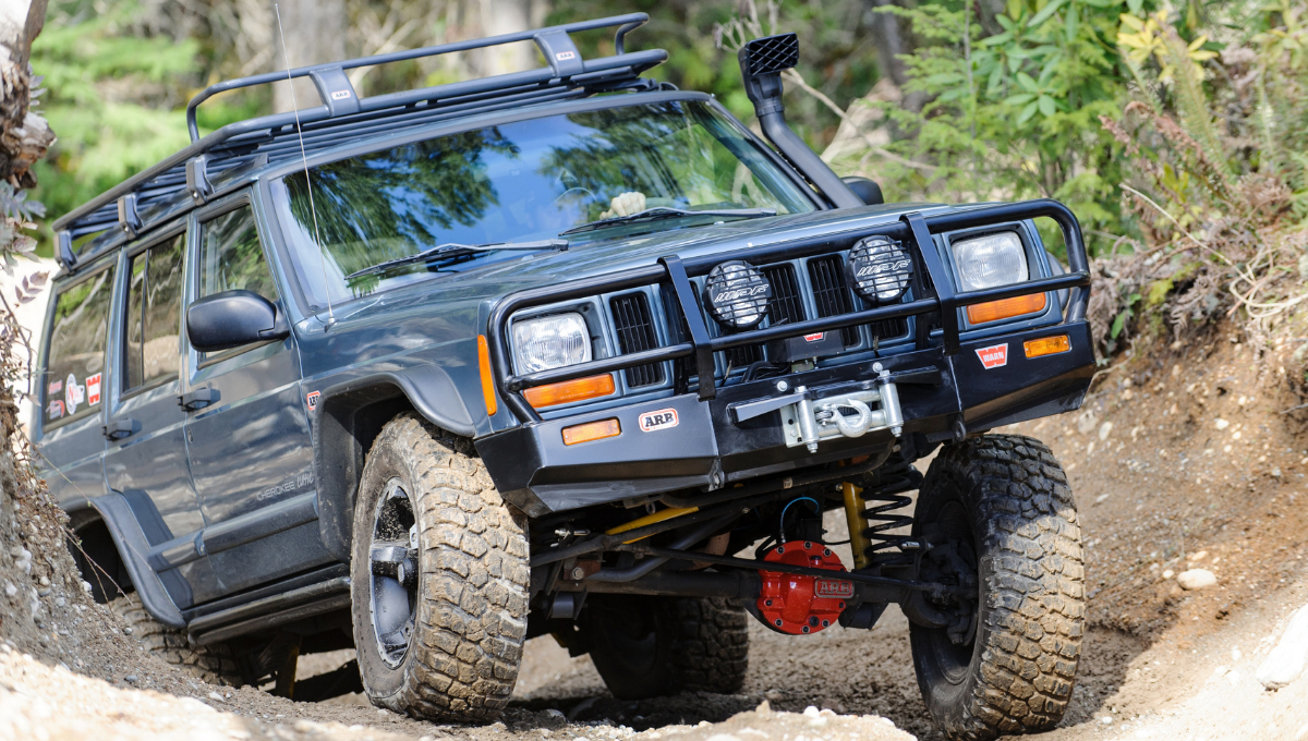 Jeep Cherokee XJ ridicat pe traseu, cu bară față ARB, troliu, snorkel și puntea față rigidă cu diferențialul vizibil