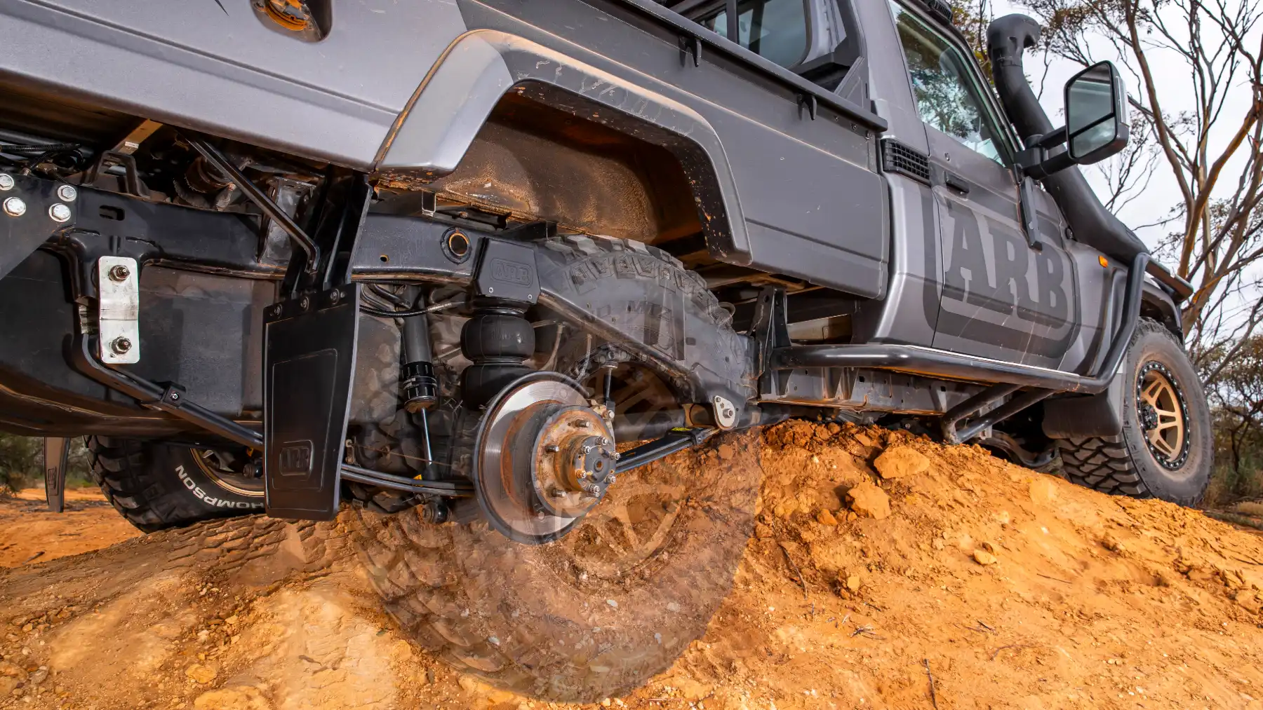 Roata spate a unui 4x4 încărcat, cu suspensia la lucru pe teren denivelat