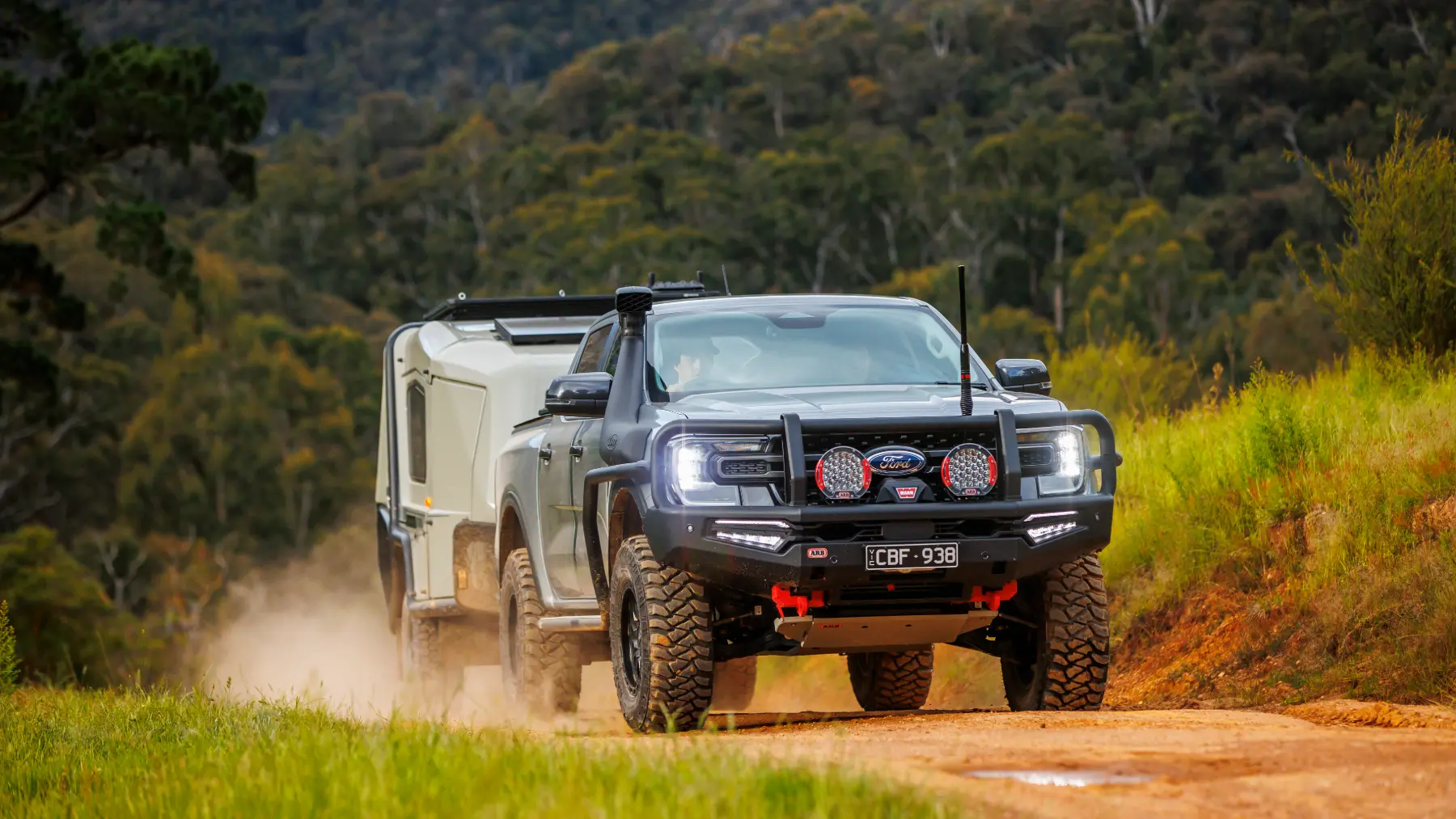 Pick-up 4x4 care tractează o rulotă de teren pe un drum de pământ