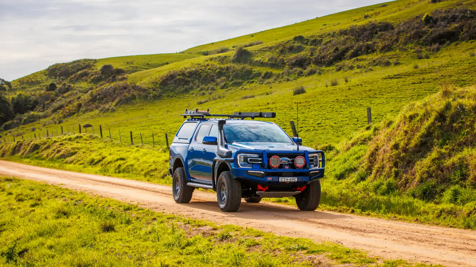 Pick-up 4x4 echipat cu hardtop, bară față și portbagaj de plafon, pe un drum de pământ