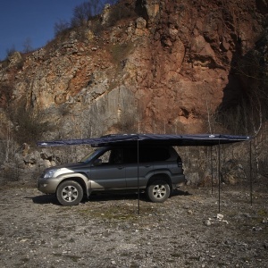 Marchiza Overlander extinsă, oferind umbră amplă lângă mașina de teren.