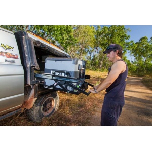 Utilizator manevrând sistemul culisant de frigider auto, coborât la nivelul solului.