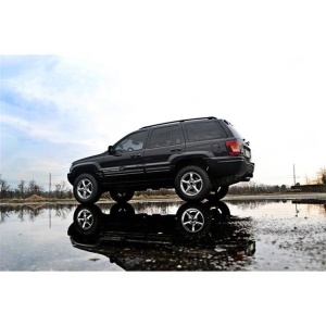 Vedere laterală a Jeep-ului Grand Cherokee cu suspensia înălțată, reflectată în apă.